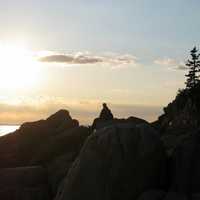 Guy watching sunset on the rocks at Acadia National Park, Maine