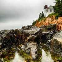 Lighthouse on the rocks on shoreline landscape