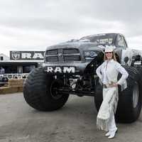 Cowgirl dressed in white standing next to monster truck in Texas
