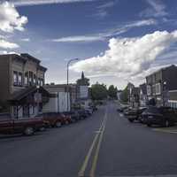 Parked Cars at the sides of the street with clouds in the sky in New Glarus