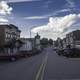 Parked Cars at the sides of the street with clouds in the sky in New Glarus