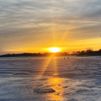 Radiant sunset over Beaver Dam Lake with 2 people walking over the ice