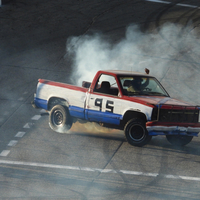 Red, white, and blue Truck burning rubber while drifting