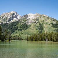 Mountains landscape across the lake with green water